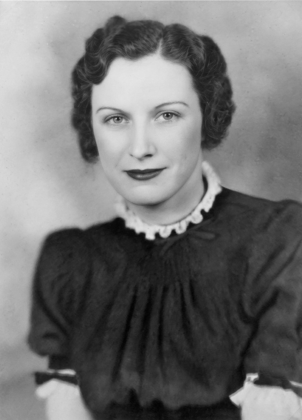 Studio portrait of Norma Maynard at twenty, smiling, in a dark dress with a white collar